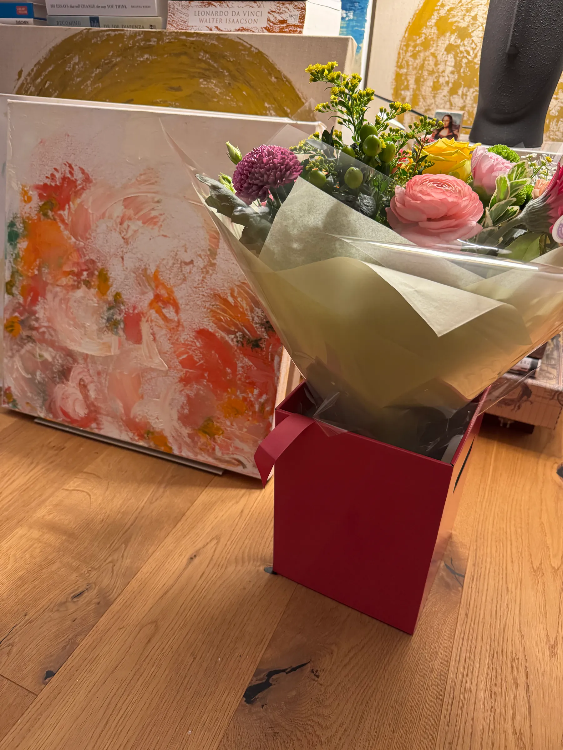 A colorful abstract painting beside a bouquet of flowers